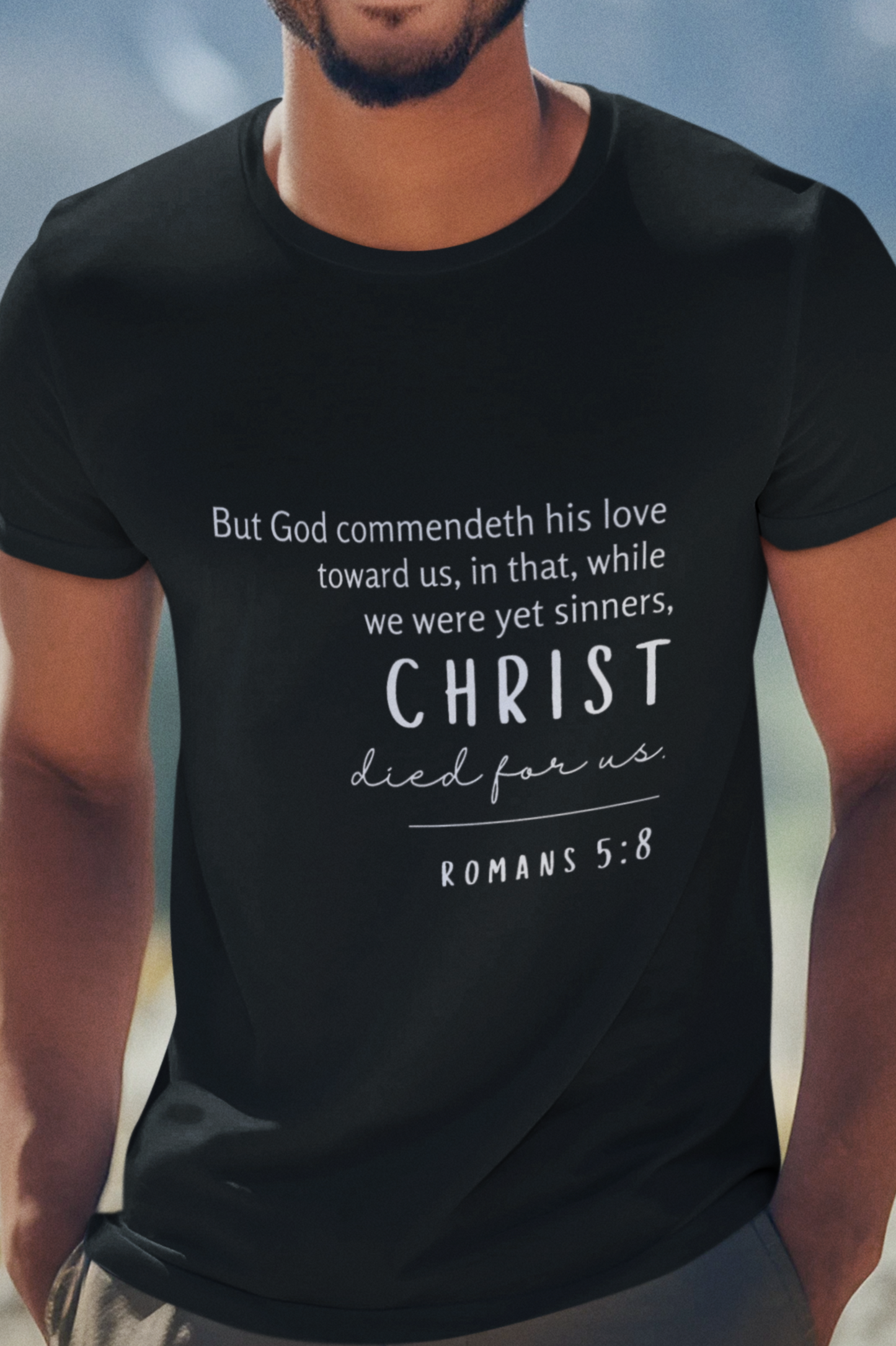 Christian T-Shirt Black with Romans 5:8 Bible verse print design. Crew neck, short-sleeved, unisex