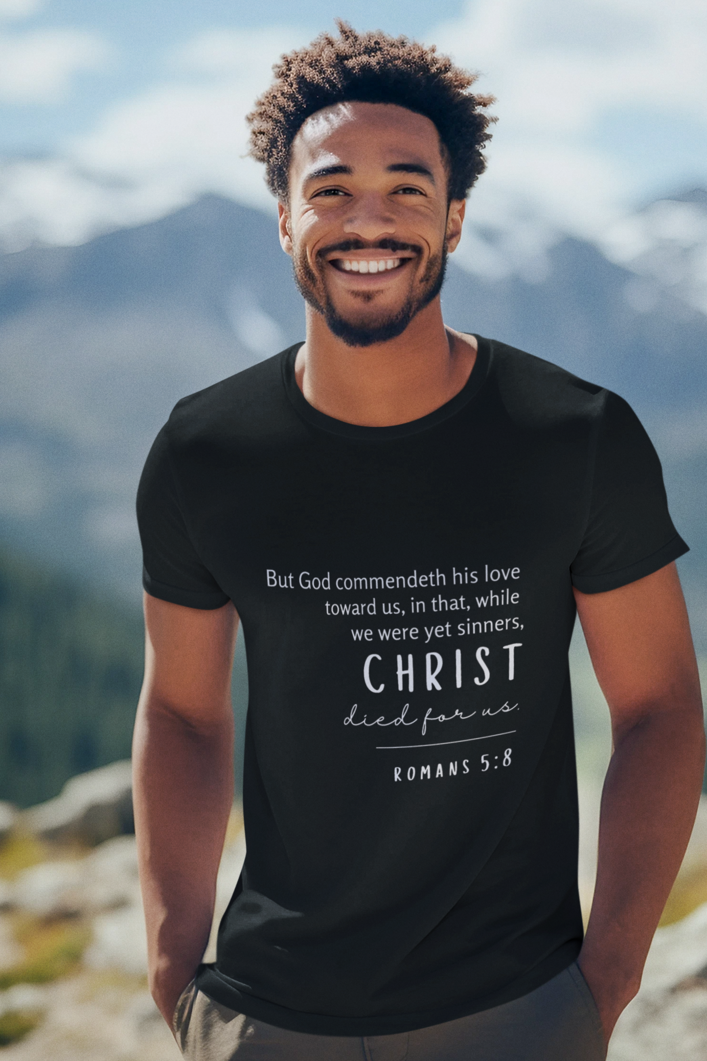 Christian T-Shirt Black with Romans 5:8 Bible verse print design. Crew neck, short-sleeved, unisex