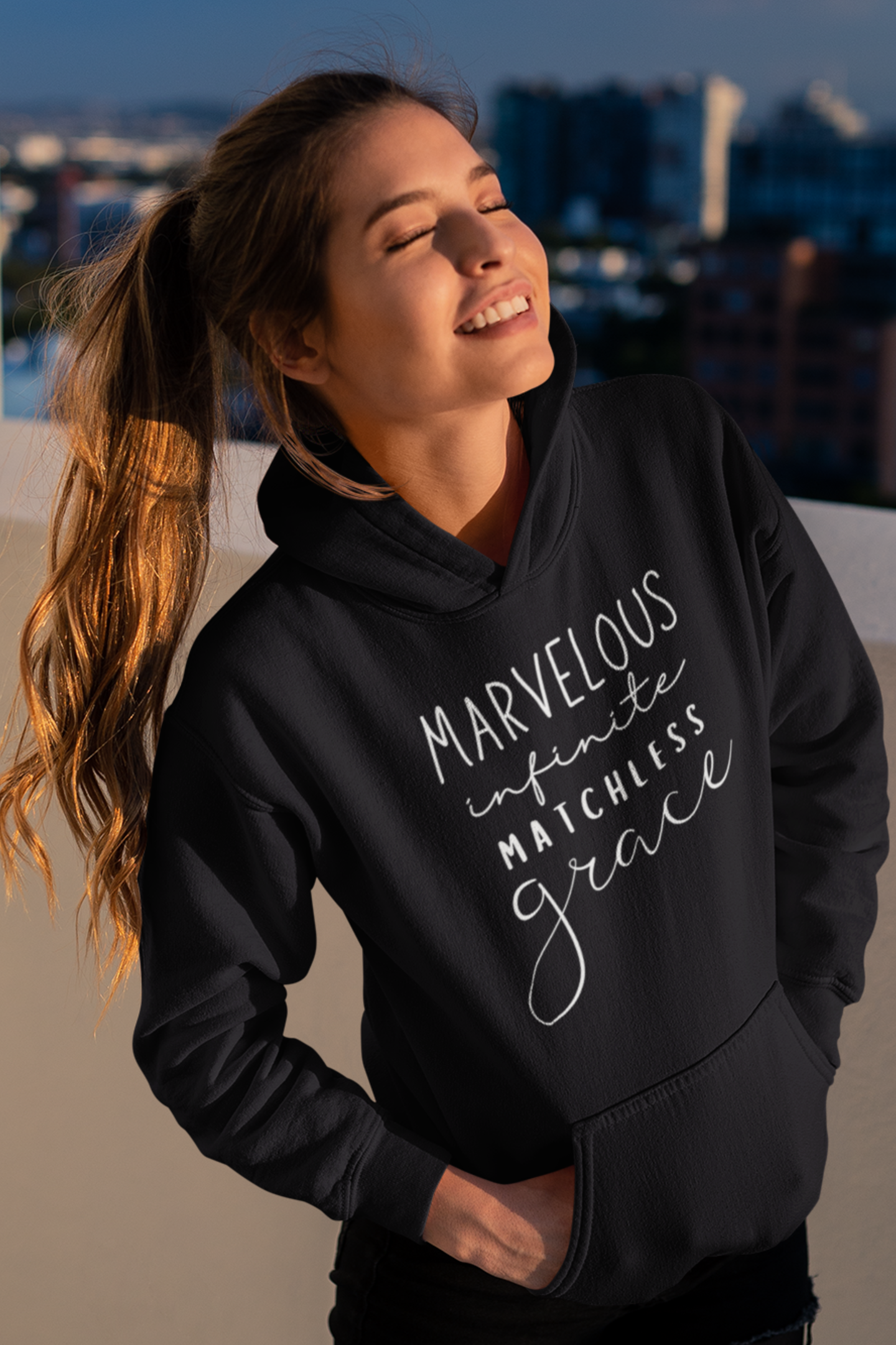 Black pullover hoodie with "Marvelous Infinite Matchless Grace" print design. Premium hoodie with large pouch pocket on the front.